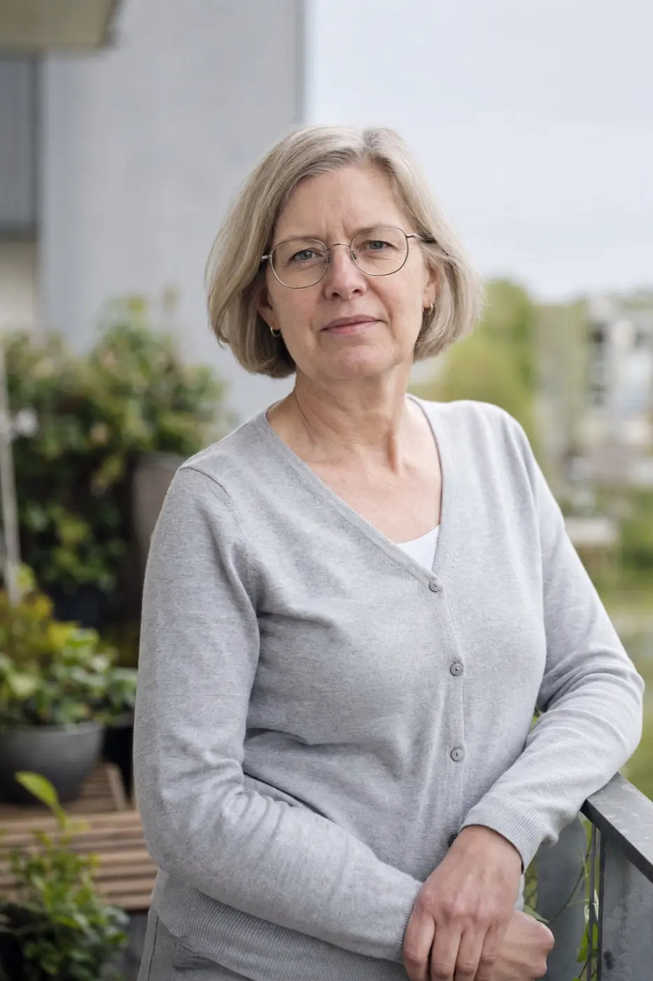 Porträt einer Frau Anfang 50 mit Brille auf ihrem Balkon.